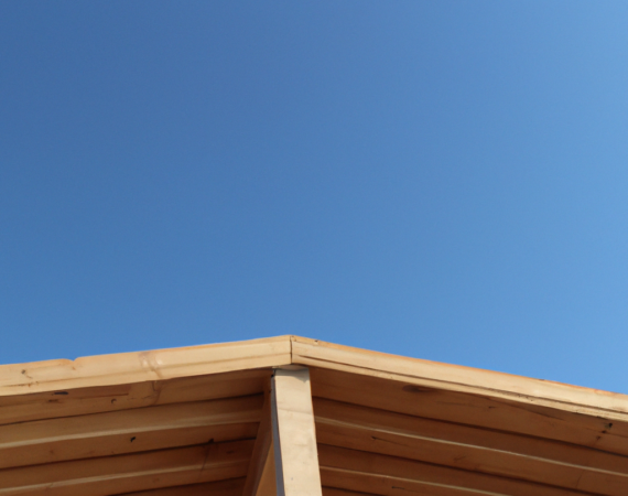 DALL·E 2023-07-12 13.13.12 - photo d'une charpente en bois moderne avec le ciel bleu en fond et que l'on voit toute la charpente sur le toit de la maison